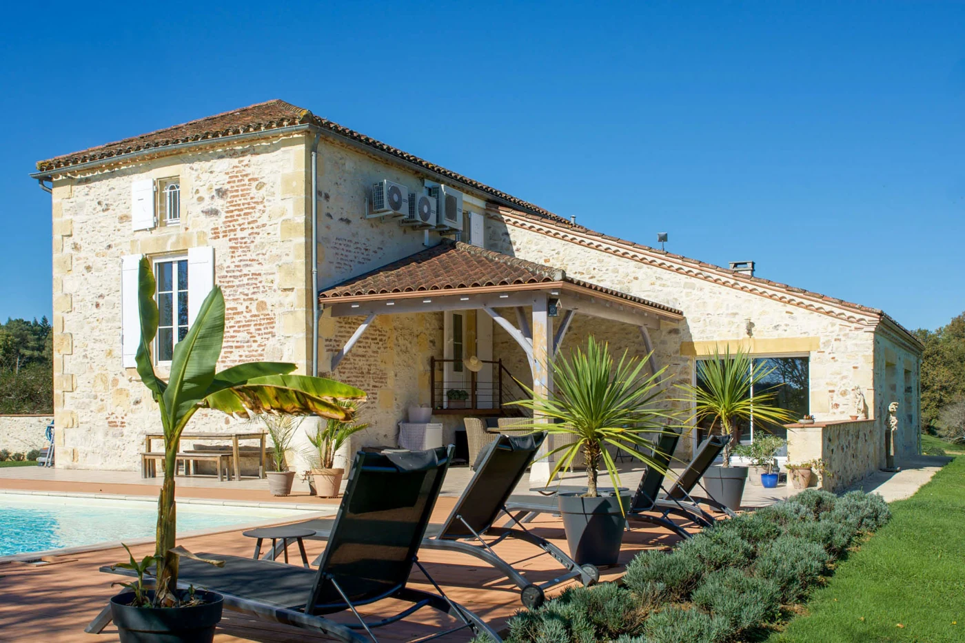 Façade en pierre et terrasse de La Maison aux Cyprès